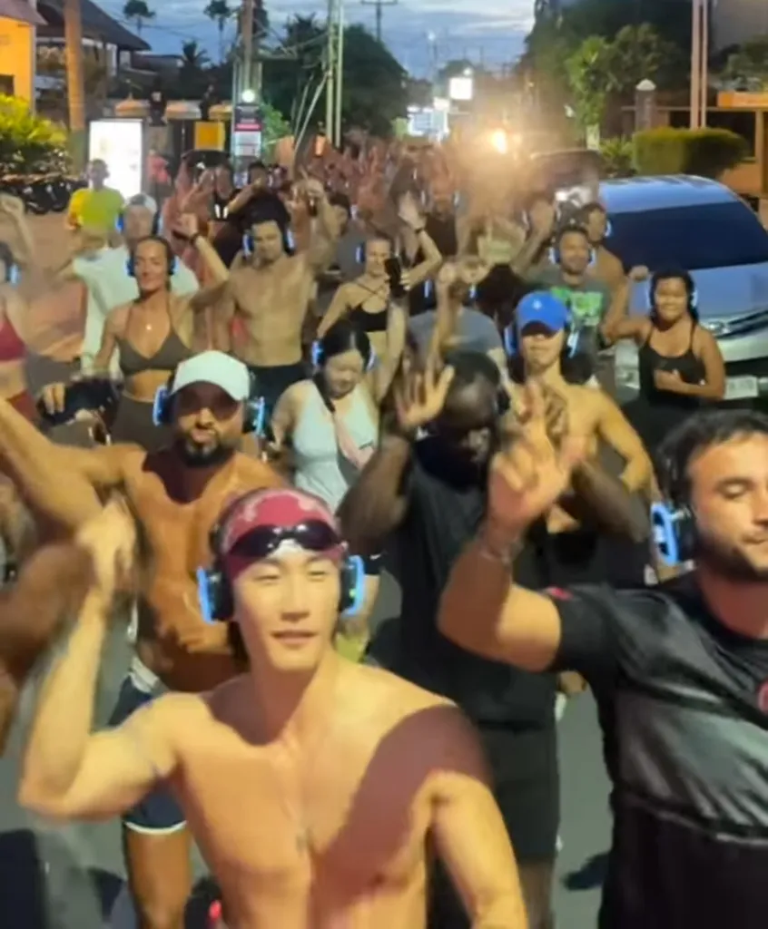 People with headphones dancing on a street at night.