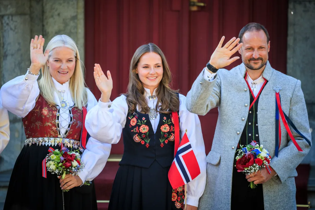 Crown Princess Mette-Marit, Princess Ingrid Alexandra, and Crown Prince Haakon Magnus waving on Norwegian Constitution Day.