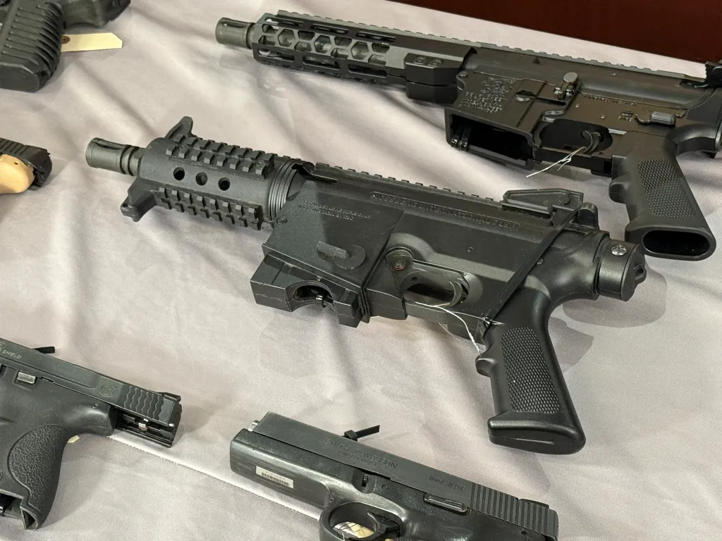 A collection of confiscated firearms including a short-barreled rifle, an assault rifle, and two handguns.