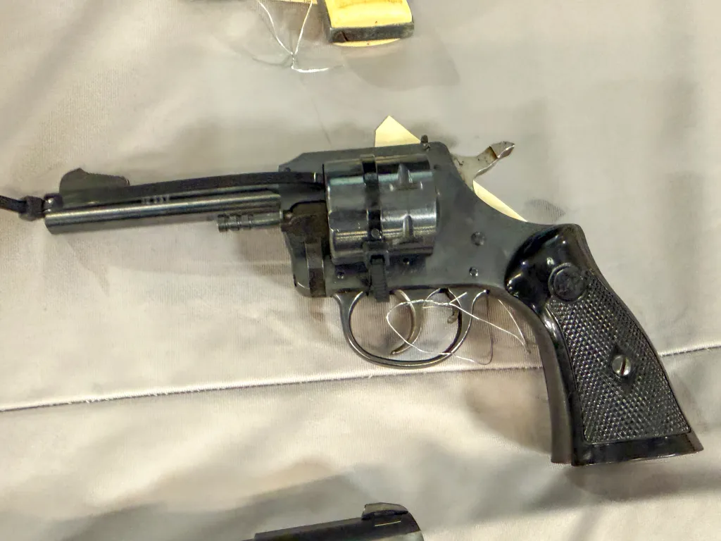 A close-up of a black revolver with a textured grip, displayed on a light-colored surface.