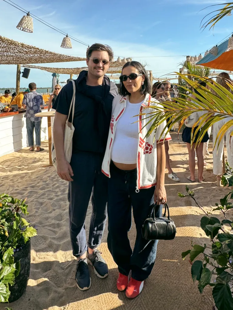 Danielle Olivera and her partner standing on a sandy outdoor patio.