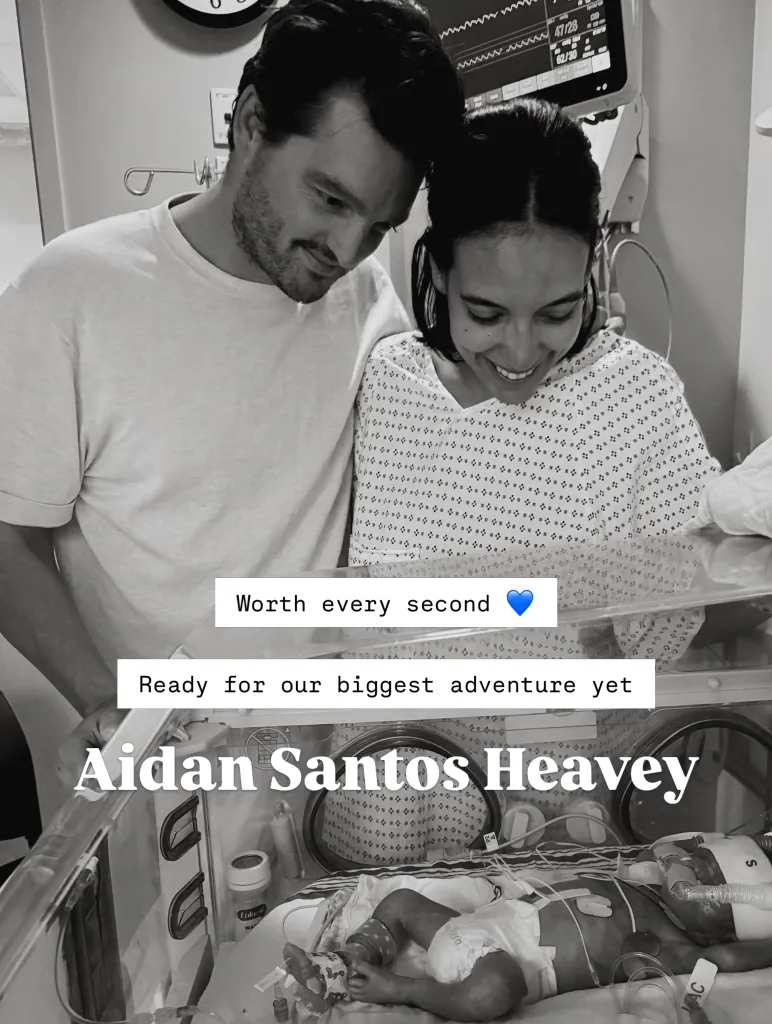 Black and white photo of Danielle Olivera and her partner looking at their newborn baby, Aidan Santos Heavey, in an incubator in the NICU.
