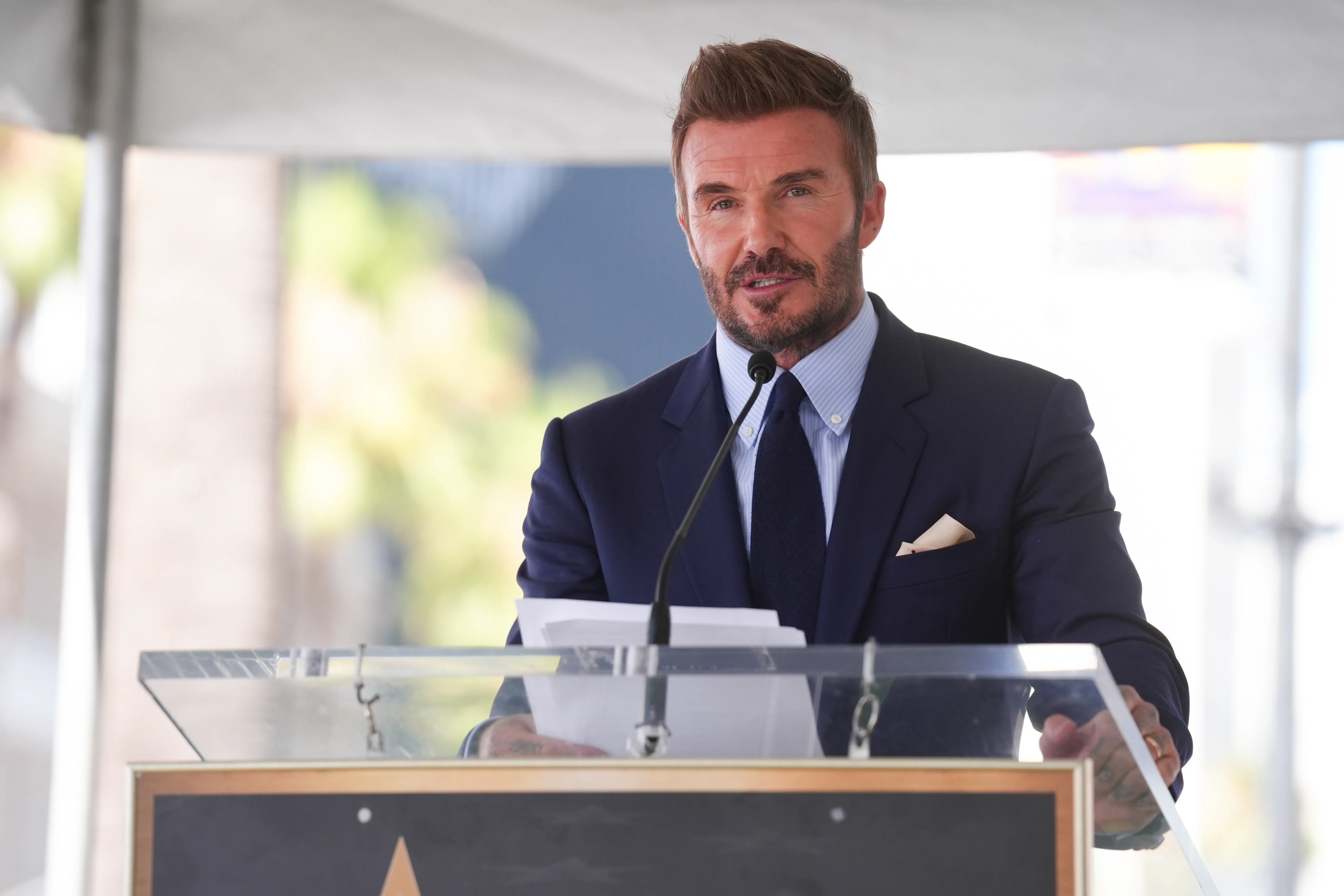 David Beckham speaking at a podium during his Hollywood Walk of Fame ceremony.
