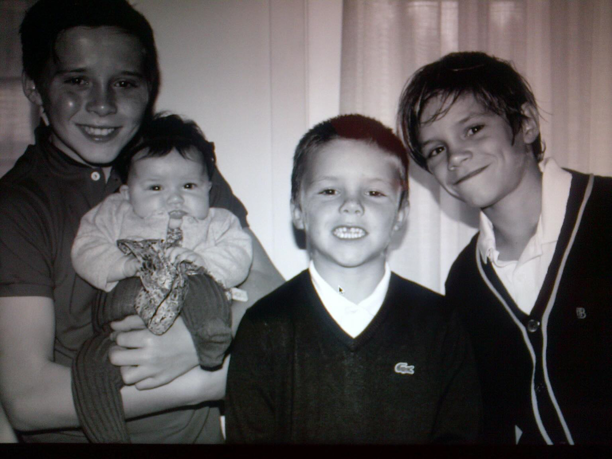 Black and white photo of four smiling children, one holding a baby.
