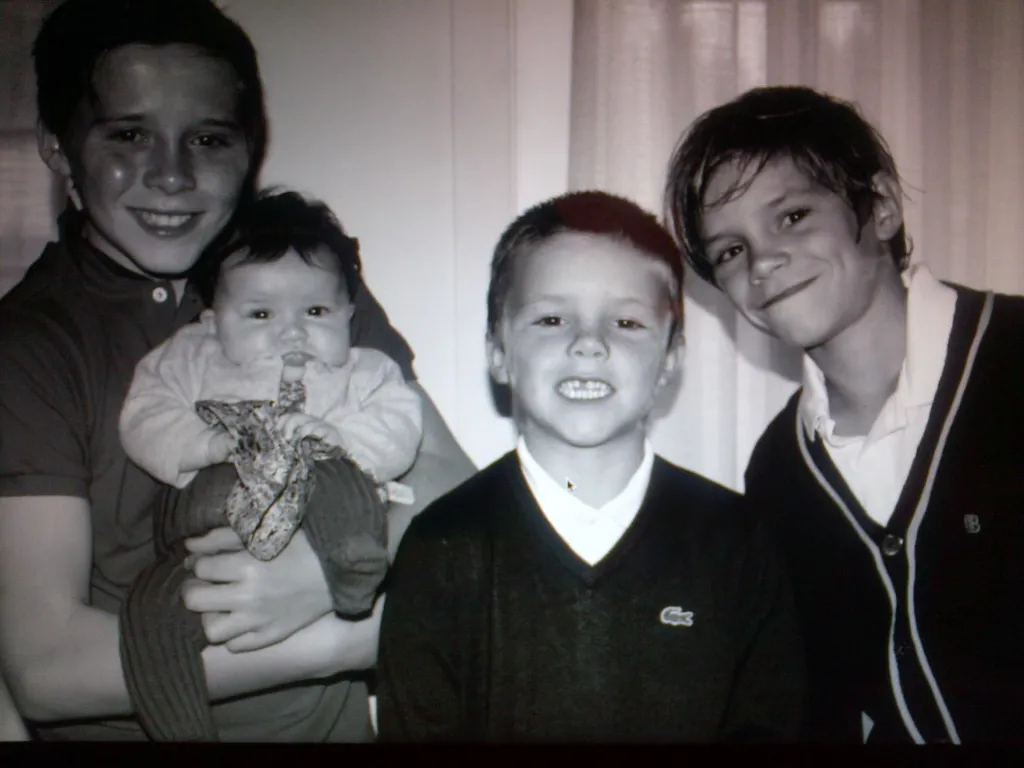 Black and white photo of four smiling children, one holding a baby.