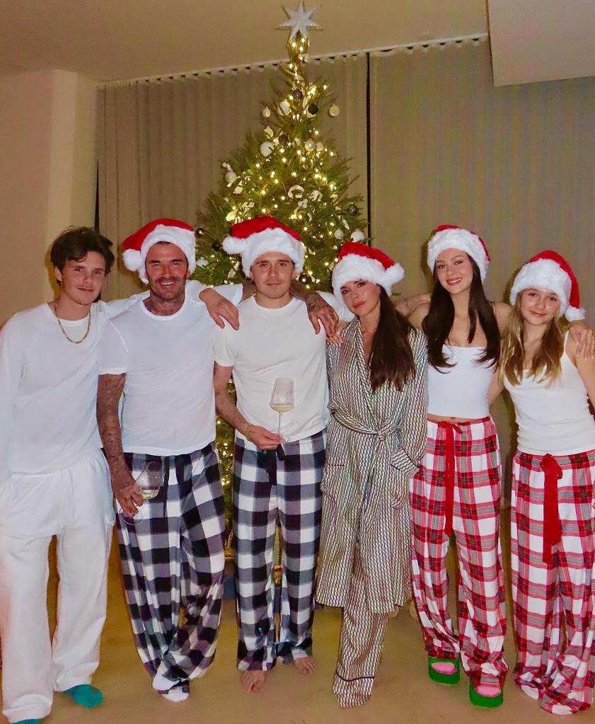 David Beckham, Brooklyn Beckham in white T-shirts and black checked pajama bottoms and Santa hats, Nicola Peltz and Harper Beckham in white tank tops and red checked pajama bottoms and Santa hats, Victoria Beckham in a Santa hat and grey striped dressing gown and pajama bottoms, Cruz Beckham in a white T-shirt and white pants.
