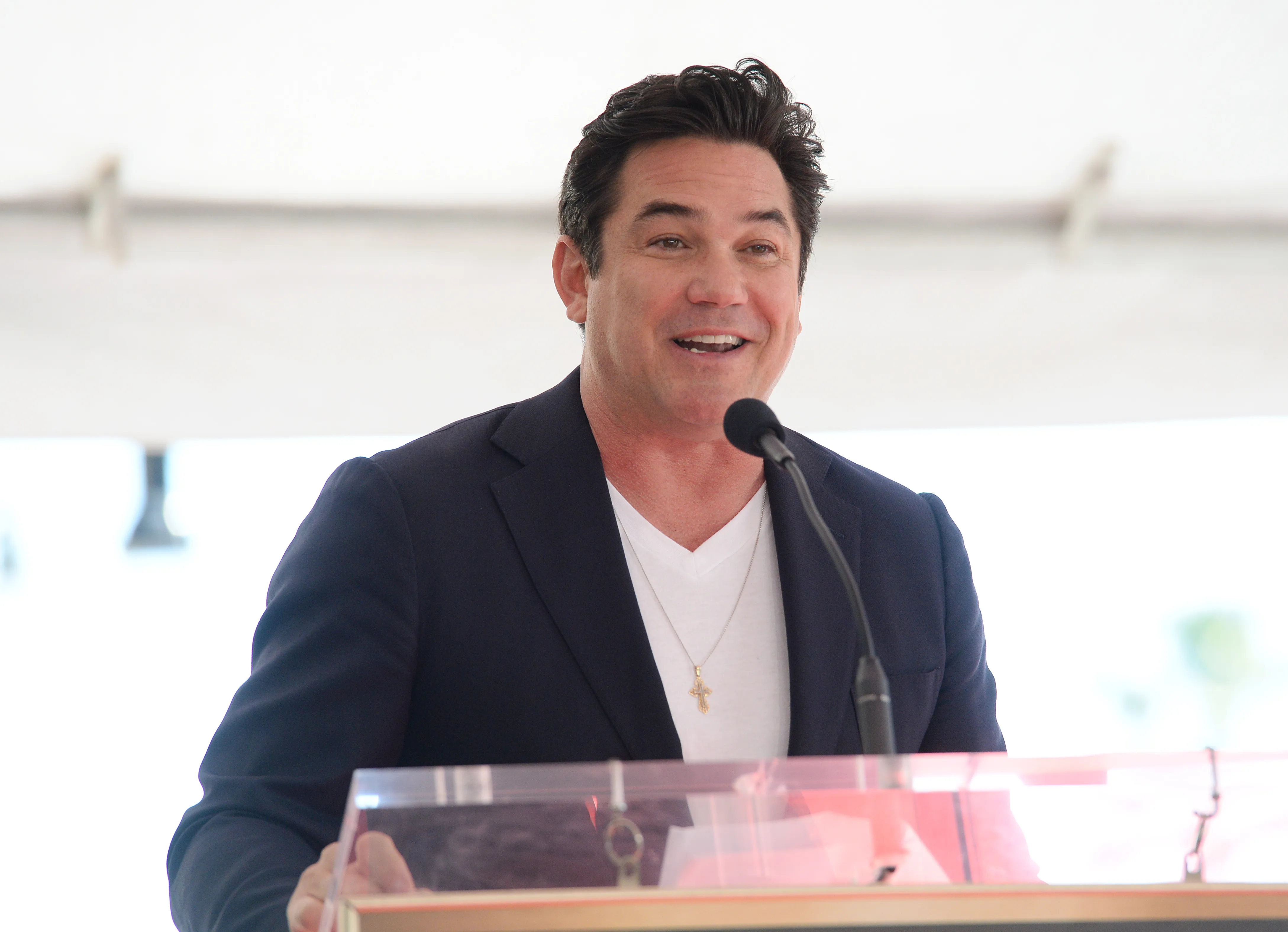 Dean Cain speaking at a podium with a microphone.