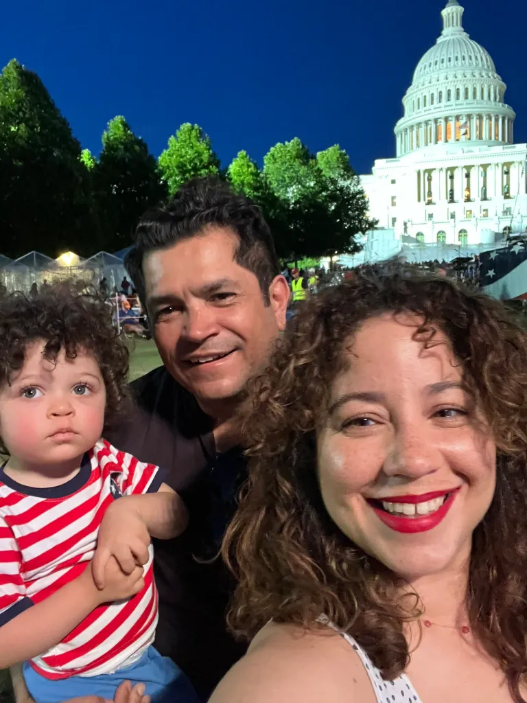 Dem Rep. Jimmy Gomez and wife Mary Hodge with their child in front of the US Capitol Building at night.