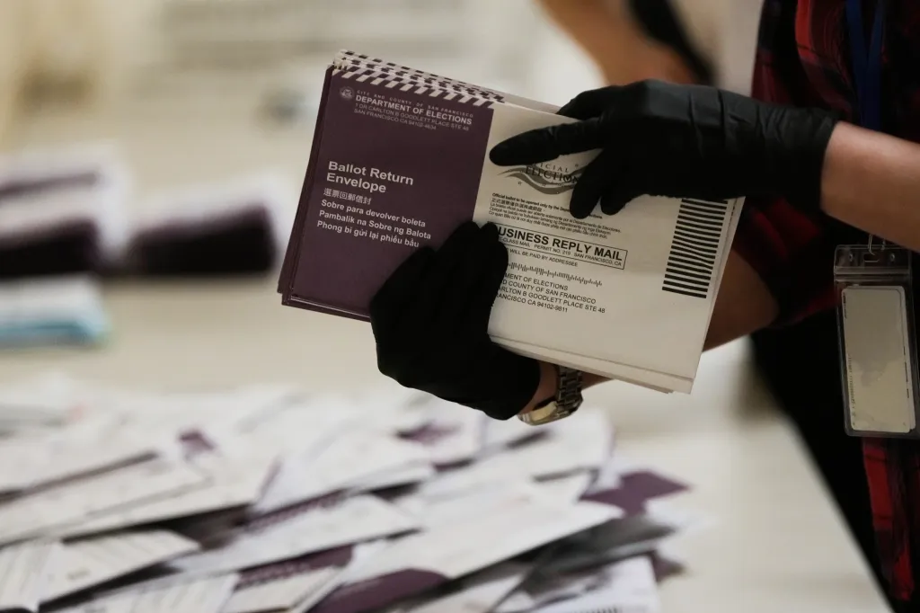 A gloved hand sorts mail-in ballots from the Department of Elections.