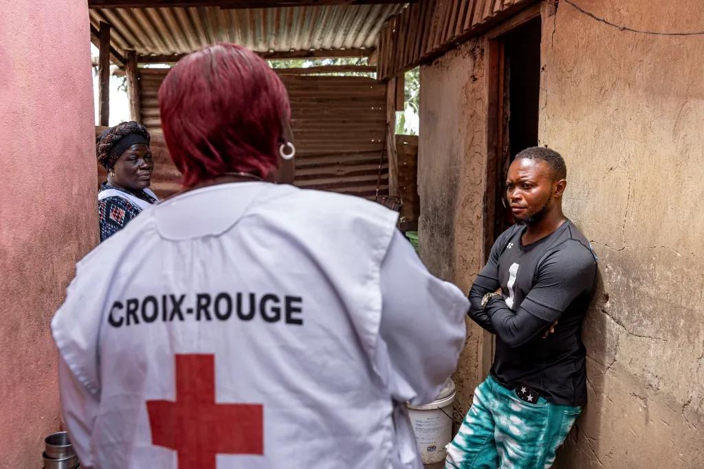 A Red Cross volunteer engages with residents in a door-to-door Ebola awareness session in Bunia, Democratic Republic of Congo.