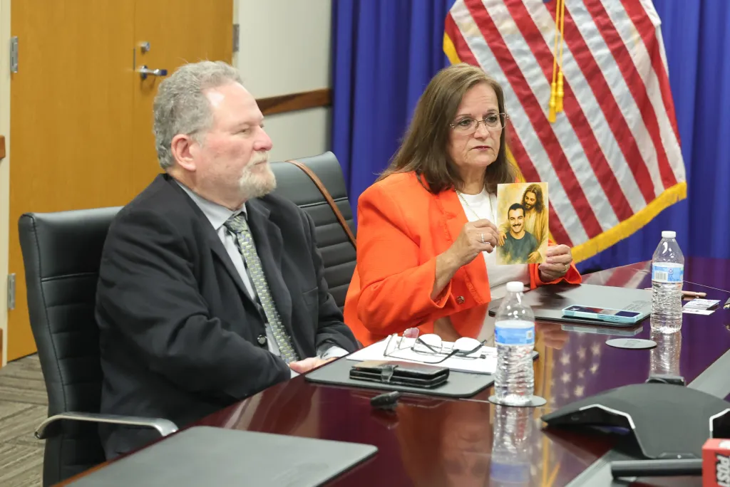 Agnes Gibboney holds a picture of a man with Jesus next to Don Rosenberg during a meeting with victims of illegal immigrant violence.