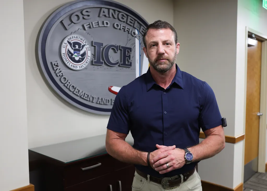 DHS Secretary Markwayne Mullin standing in front of the Los Angeles ICE Field Office seal.