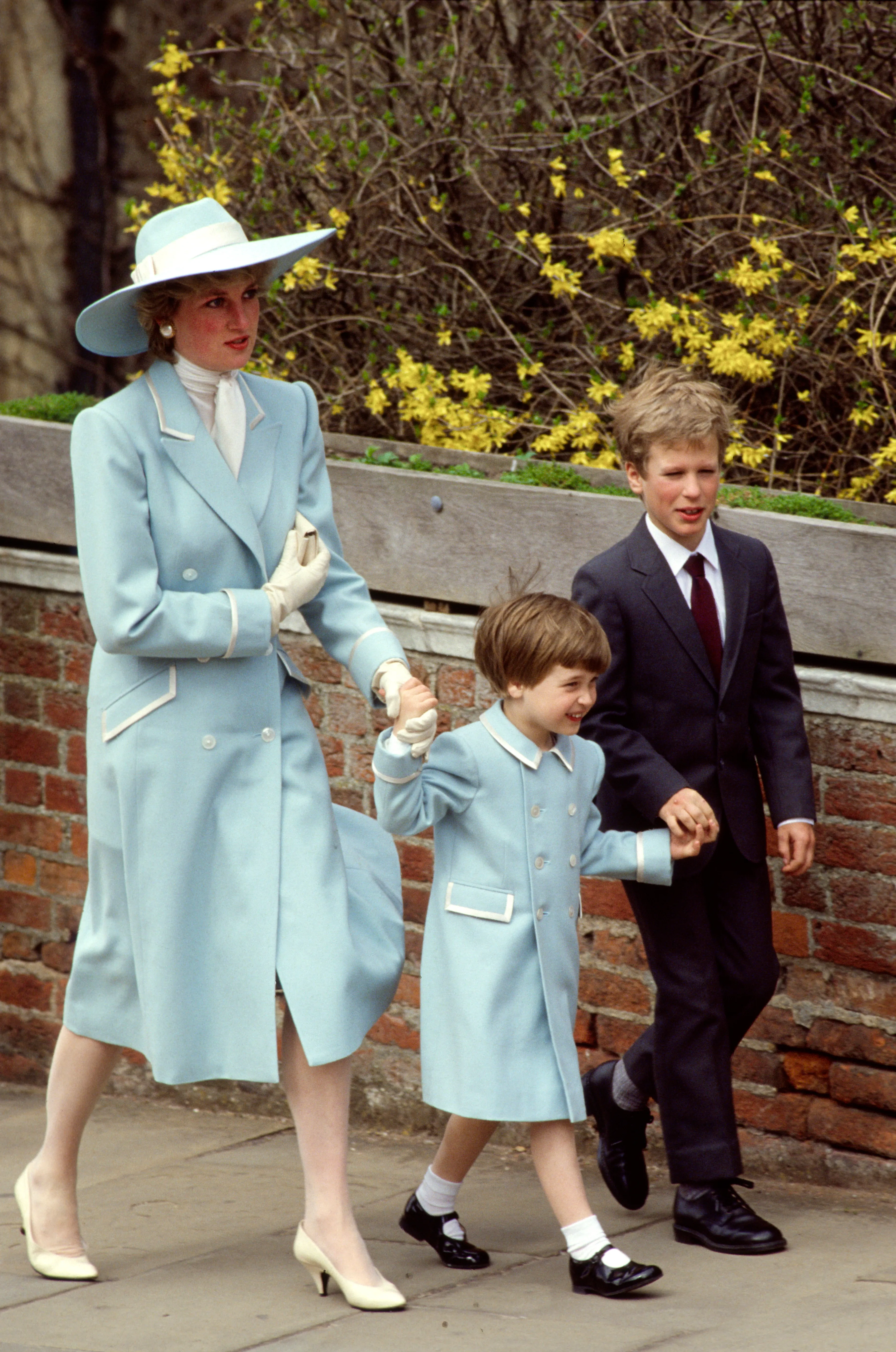 Diana, Princess of Wales, holding hands with her son Prince William and her nephew Peter Phillips, all in light blue coats by Catherine Walker, on their way to Easter service.
