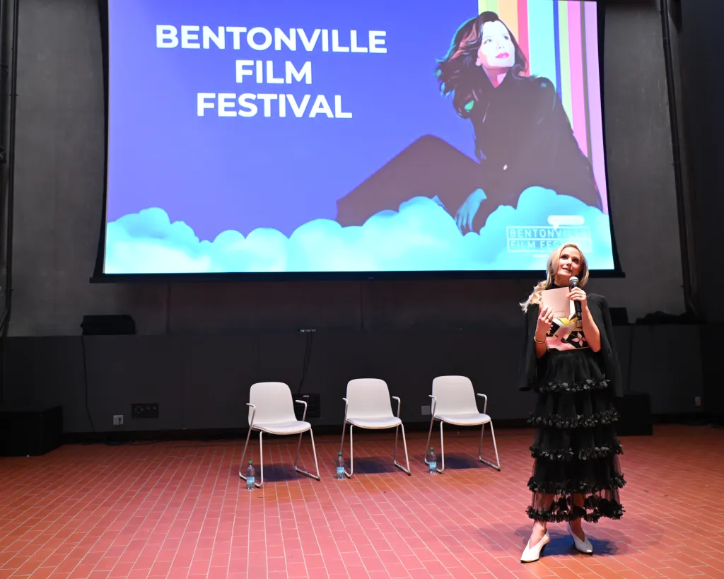 Jennifer Siebel Newsom speaking at the Bentonville Film Festival, with a screen behind her showing 