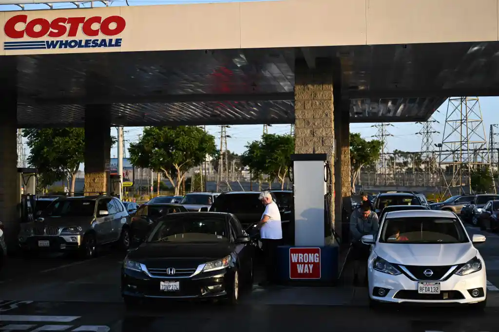 People pump gasoline into vehicles at a Costco Wholesale gas station.