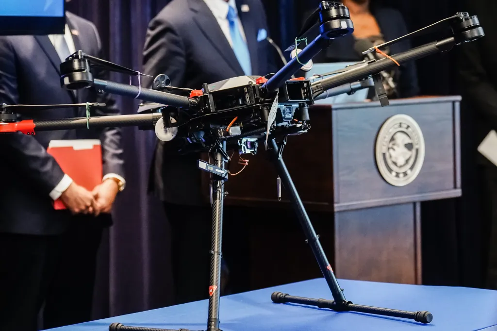 Men standing behind a podium and a table with a drone on it.