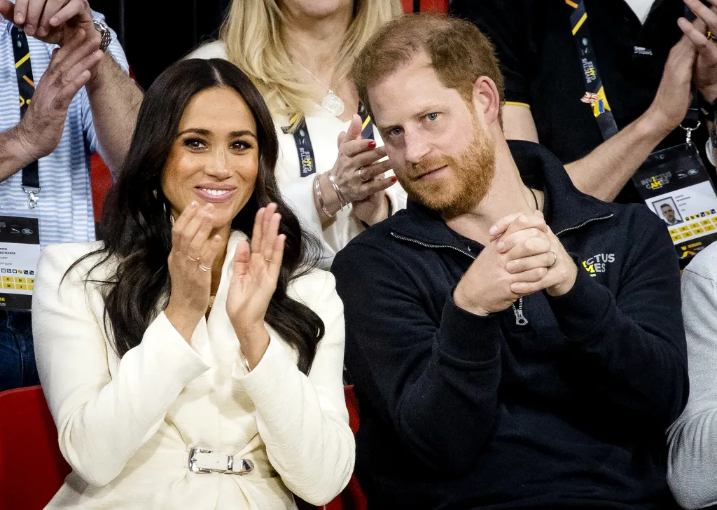 Meghan Markle claps while Prince Harry sits beside her at the Invictus Games.