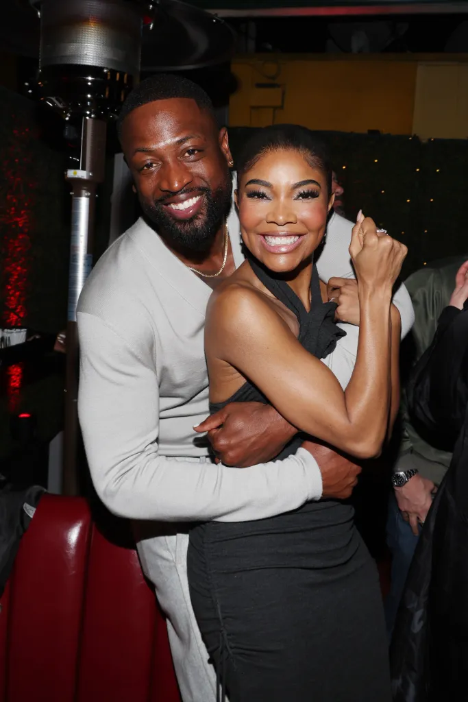 Dwyane Wade and Gabrielle Union smiling and embracing at an album release party.