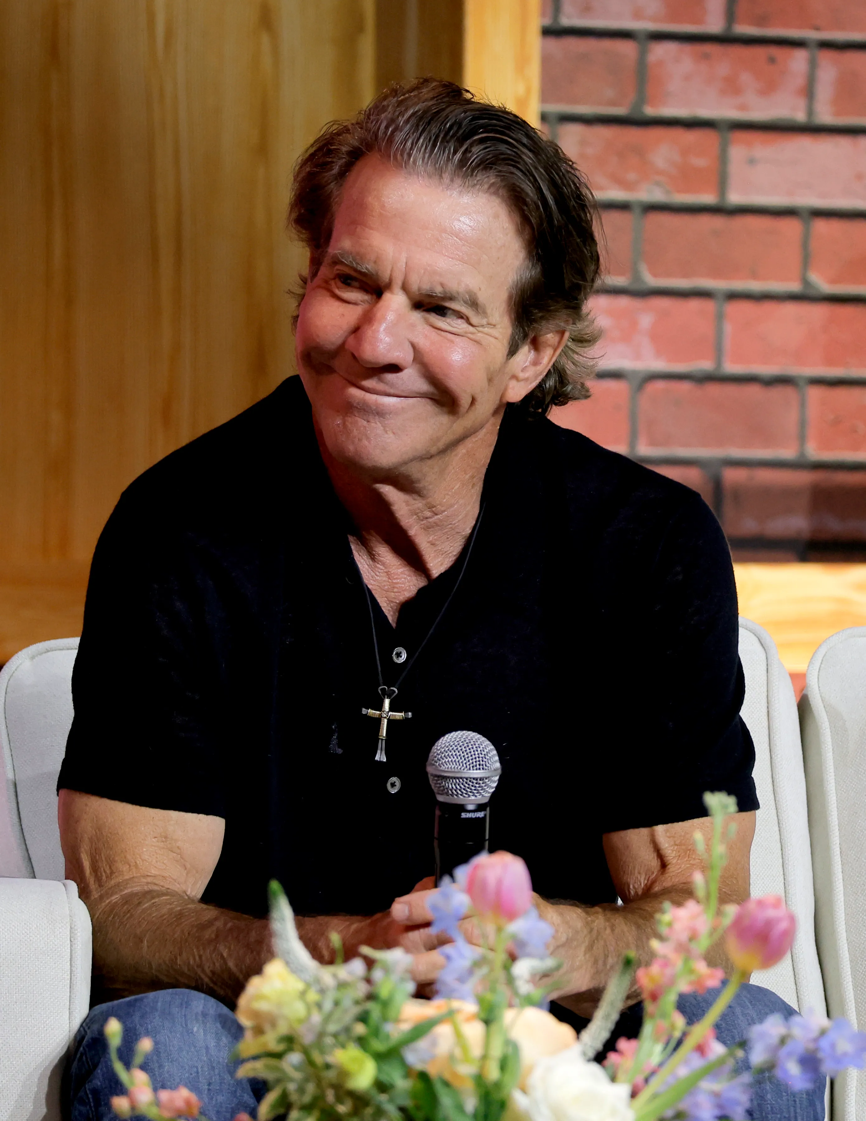 Dennis Quaid smiling and holding a microphone at CMA Fest.