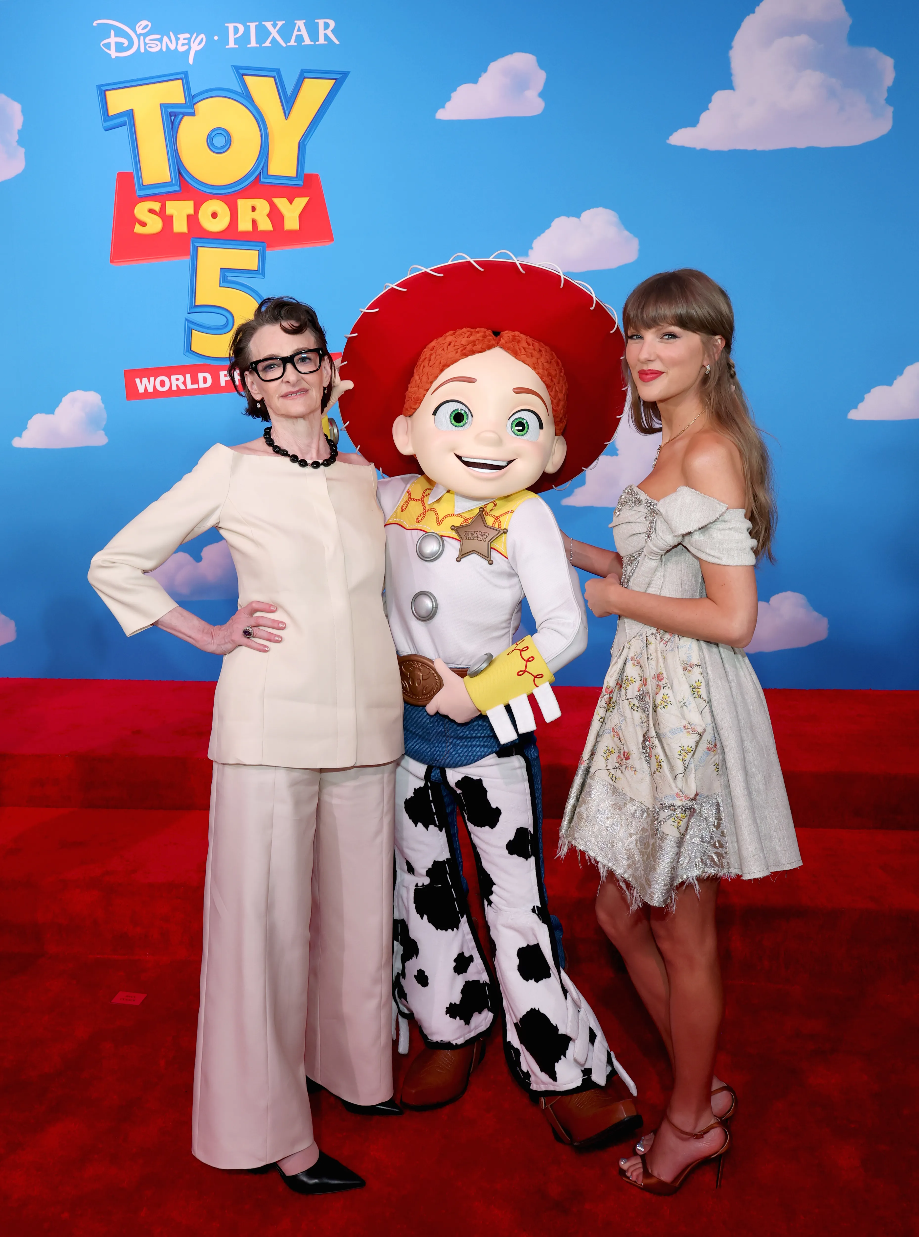 Joan Cusack and Taylor Swift posing with a person dressed as Jessie from Toy Story at the film's premiere.