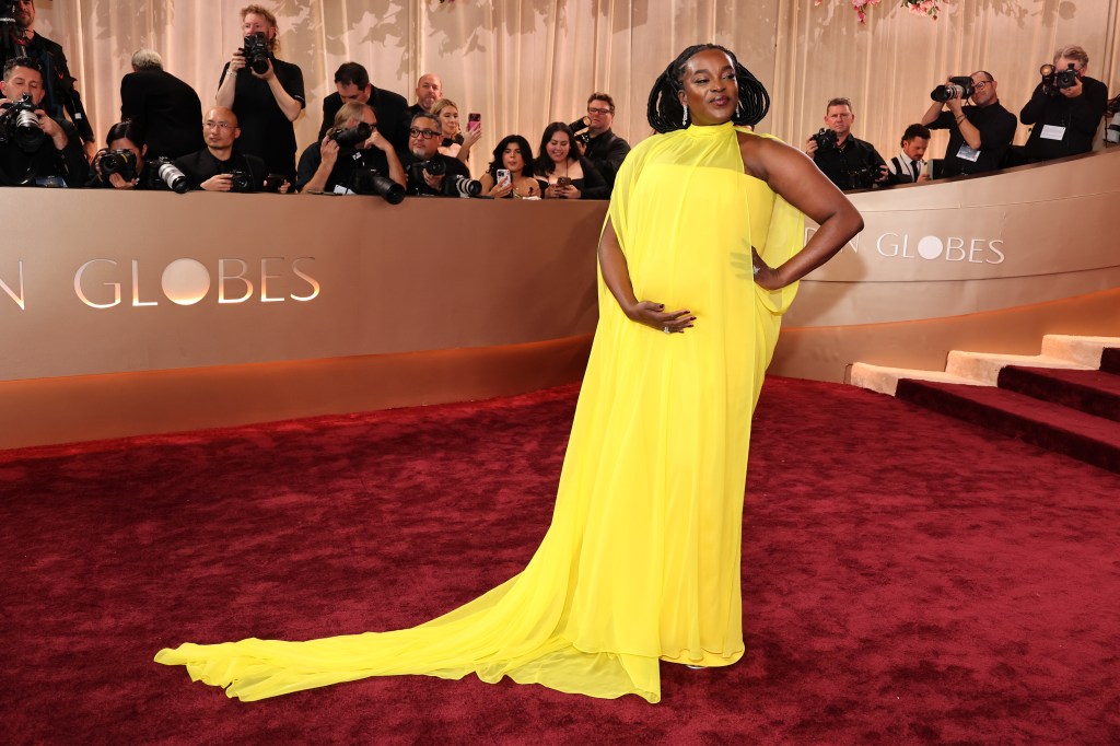 Wunmi Mosaku poses in a flowing yellow gown on the red carpet at the Golden Globes.