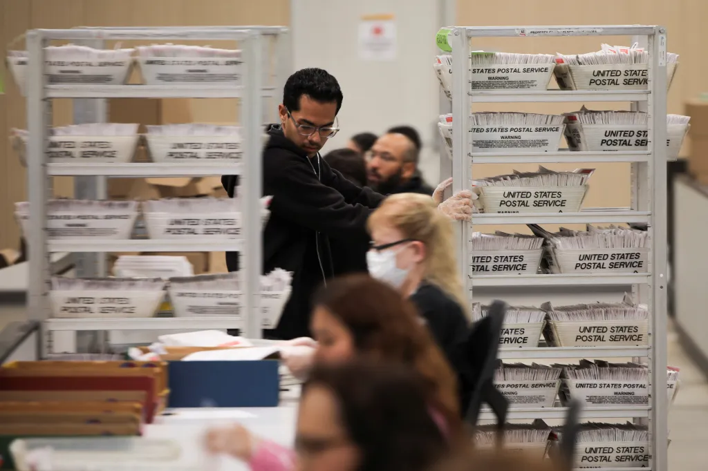 An election worker wearing gloves processes ballots during the California primary election.