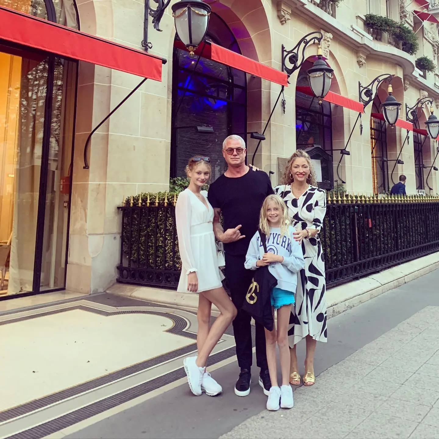 Eric Dane, Rebecca Gayheart, and their children posing in front of a building with red awnings.