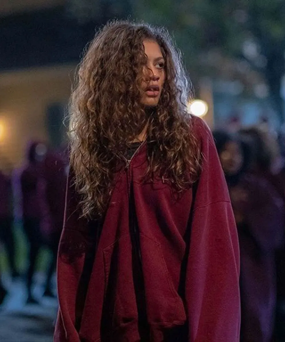Rue in a maroon hoodie with a worried expression.