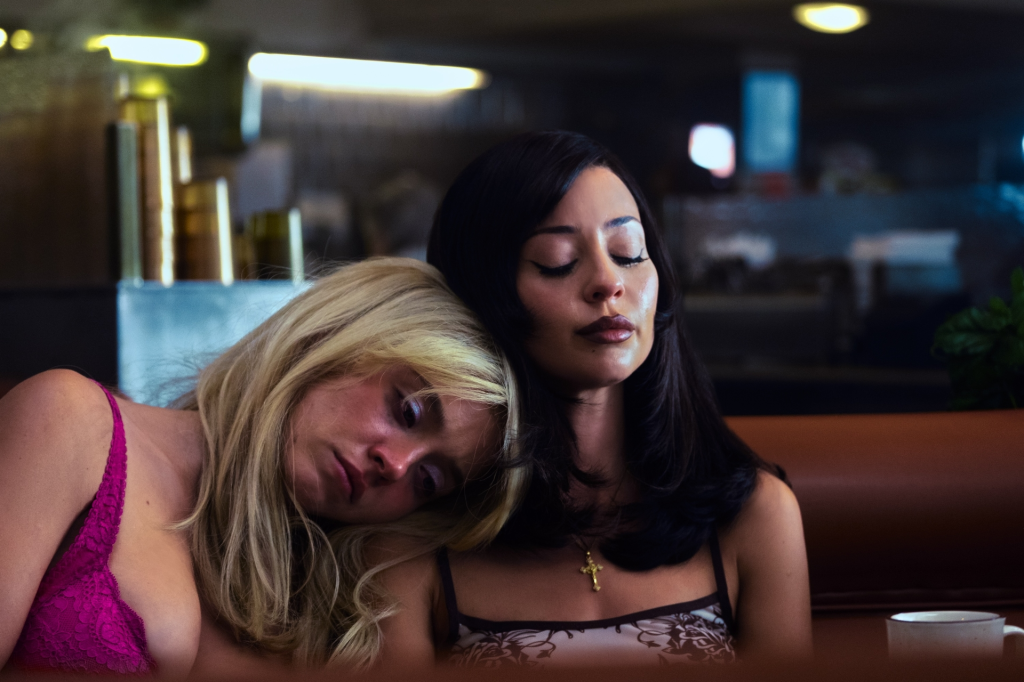 Two women, one blonde and one brunette, resting their heads on each other's shoulders.