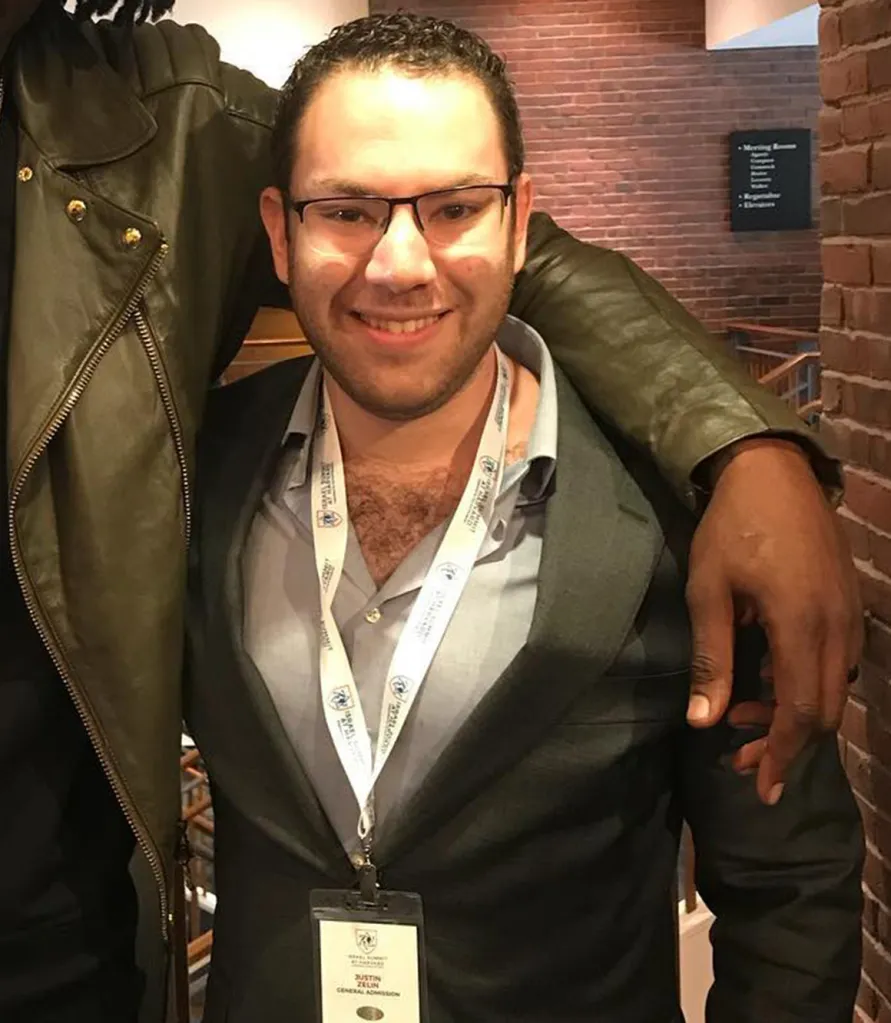 Justin Zelin smiling with another person's arm around him.