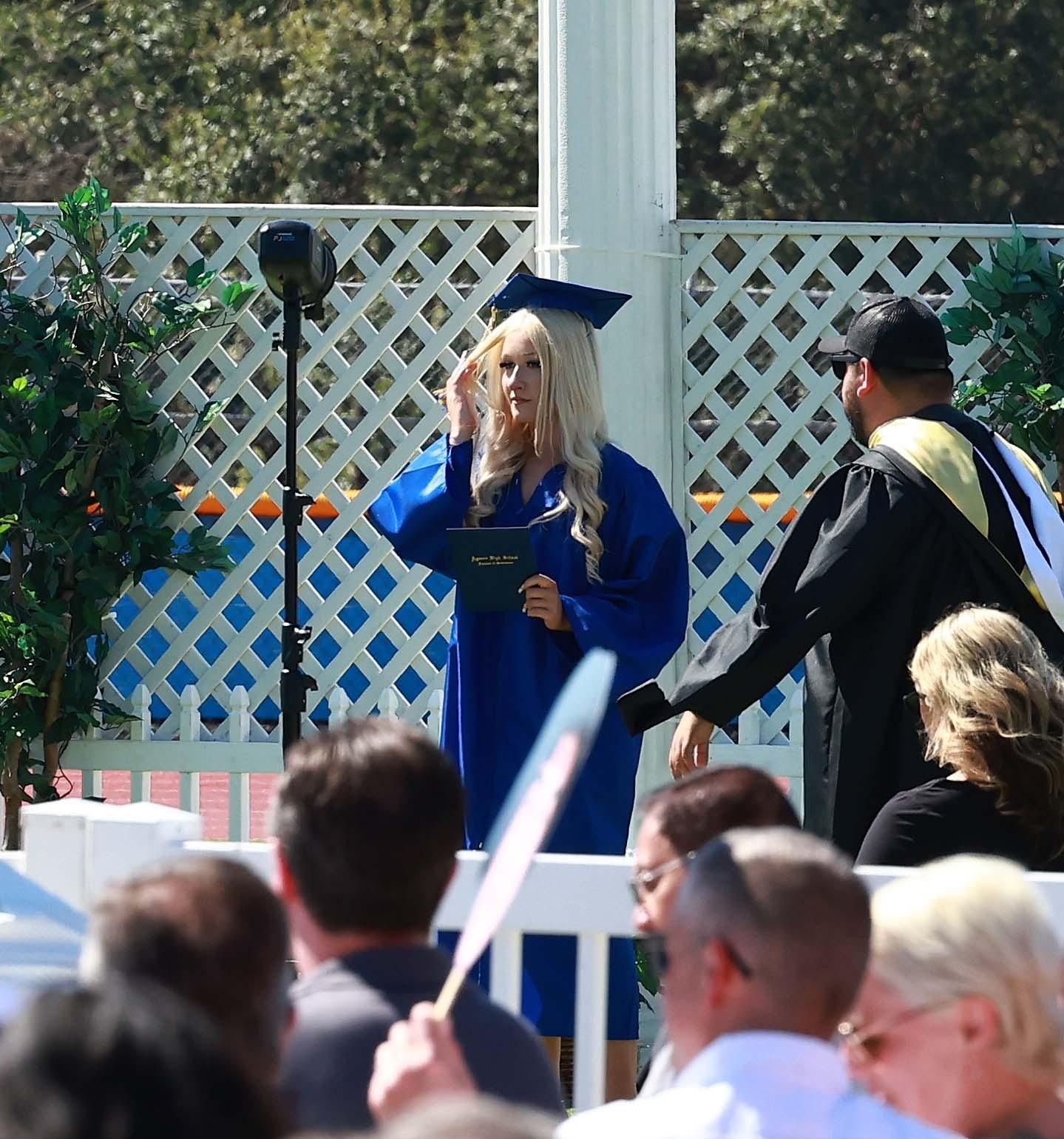 Stella McDermott in a blue graduation gown and cap, holding her diploma.