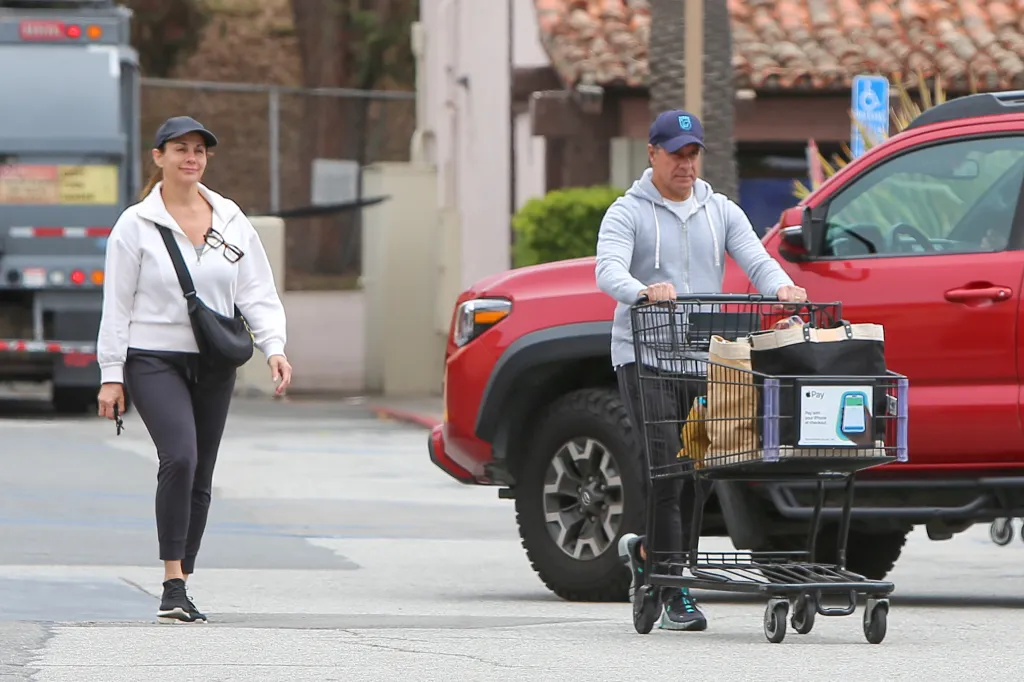 Alberto Carvalho pushing a shopping cart filled with groceries and his wife walking next to him.