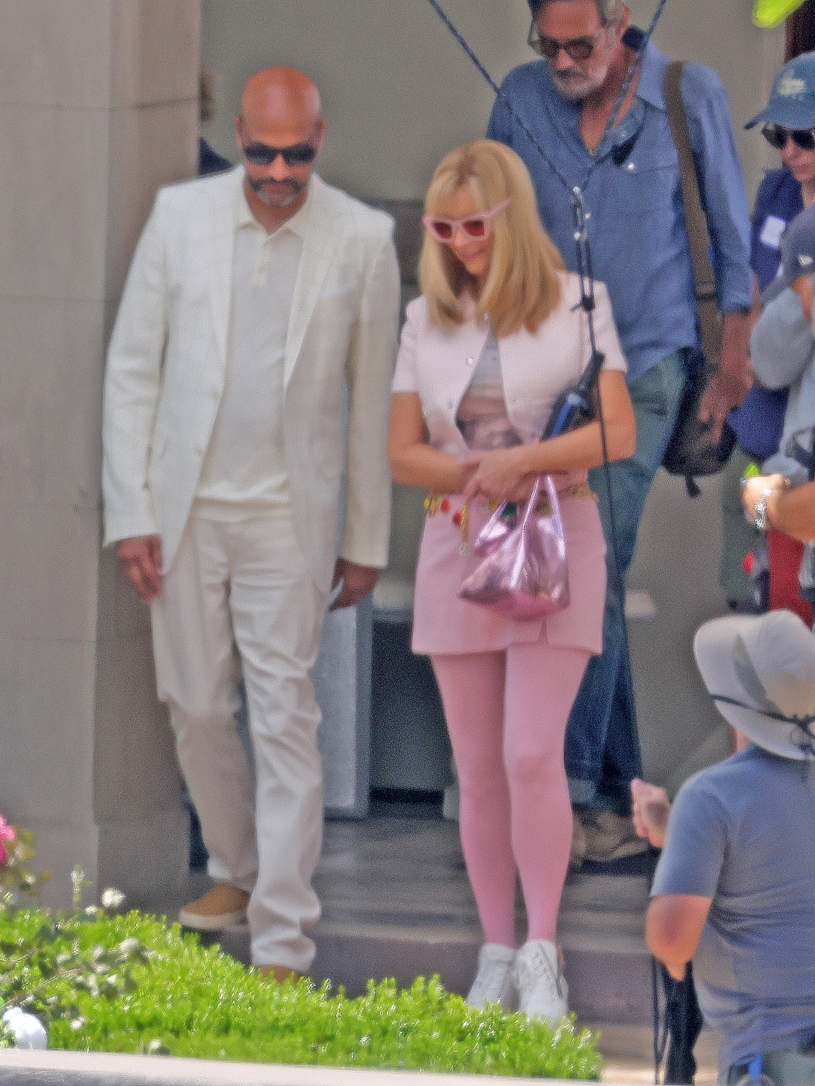 Lisa Kudrow in a pink outfit with Keegan-Michael Key in a white suit on set.