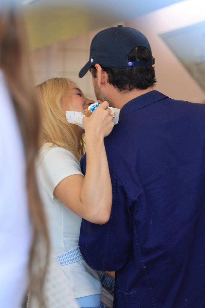 Sydney Sweeney and Scooter Braun share a kiss while Sweeney holds a treat.