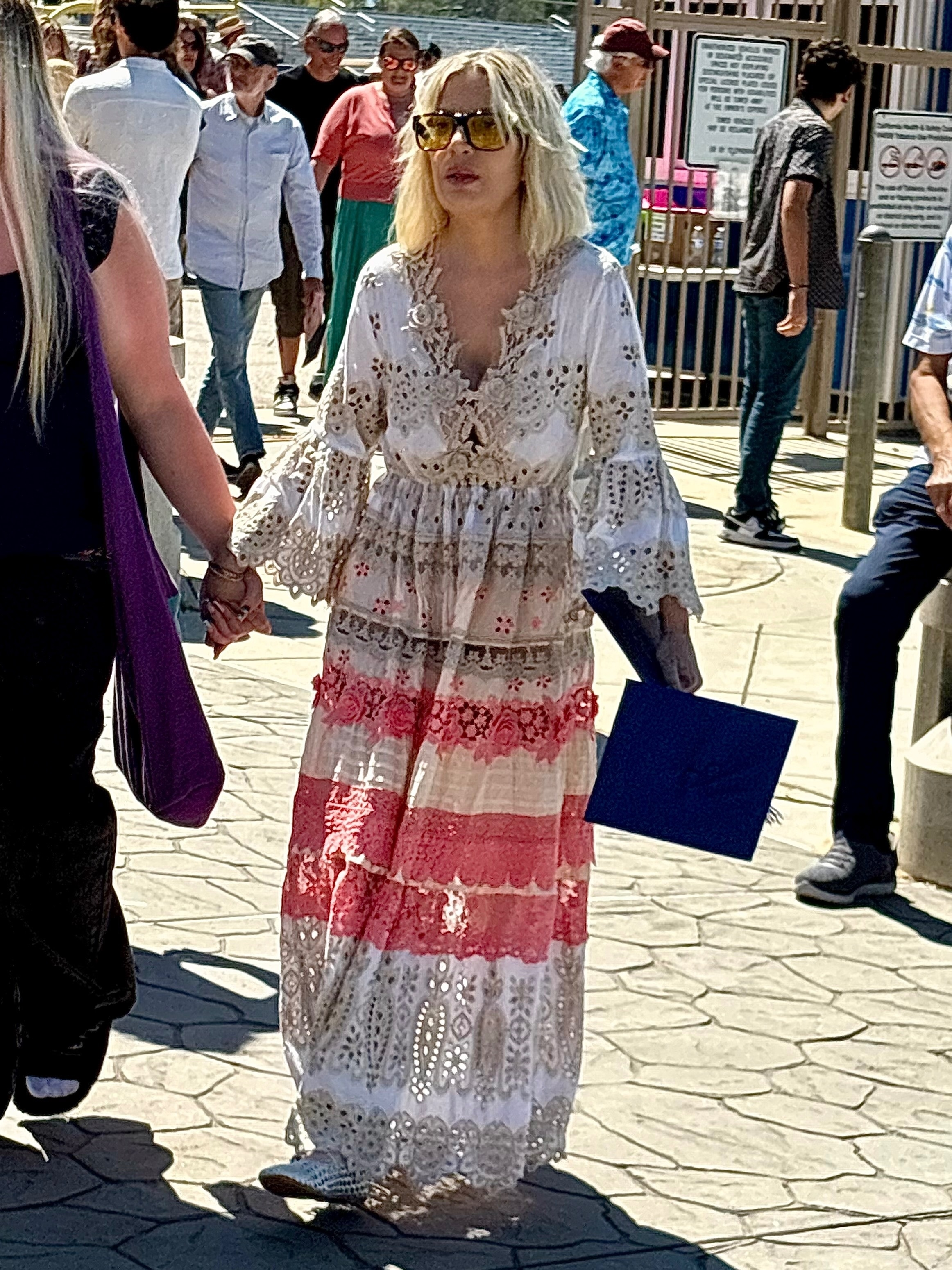 Tori Spelling in a white and pink dress holding her daughter's graduation cap.