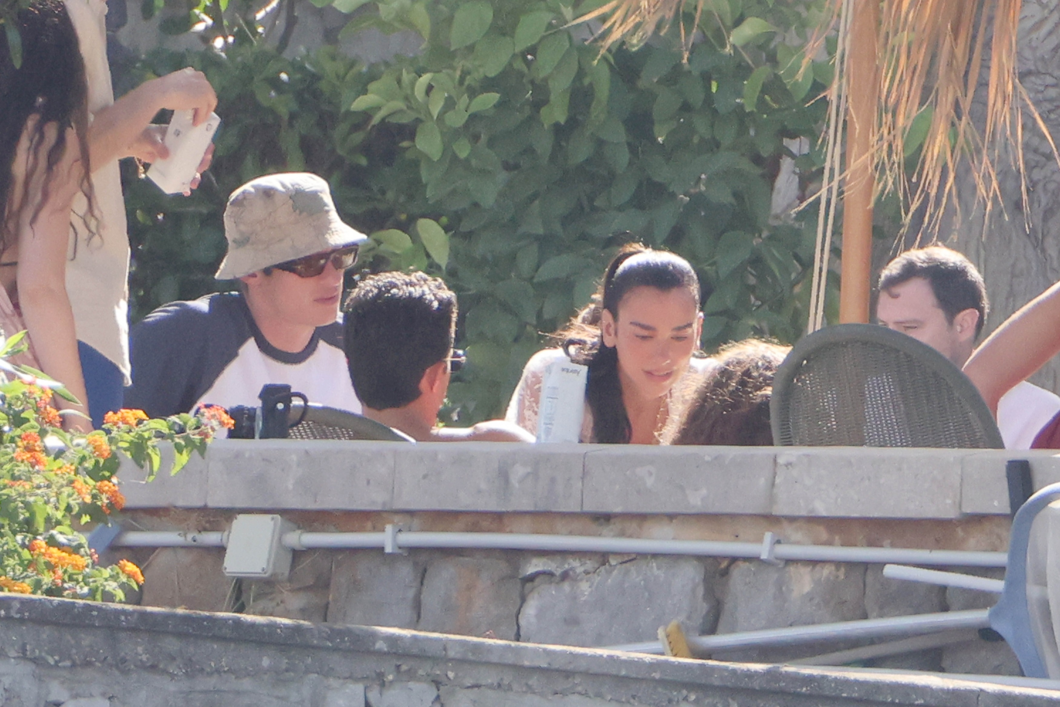 Dua Lipa and Callum Turner with friends at a post-wedding gathering.