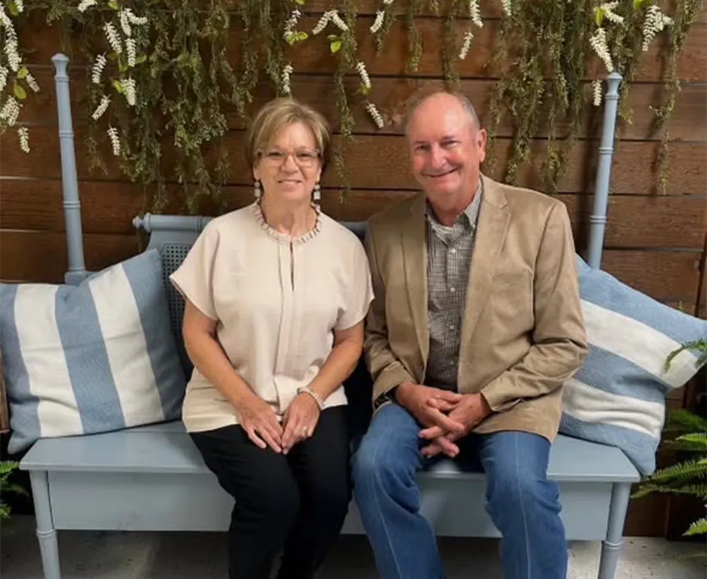 Photo of Billy Blair, 74, and his wife, Virginia Carol Blair, 71, sitting on a bench.