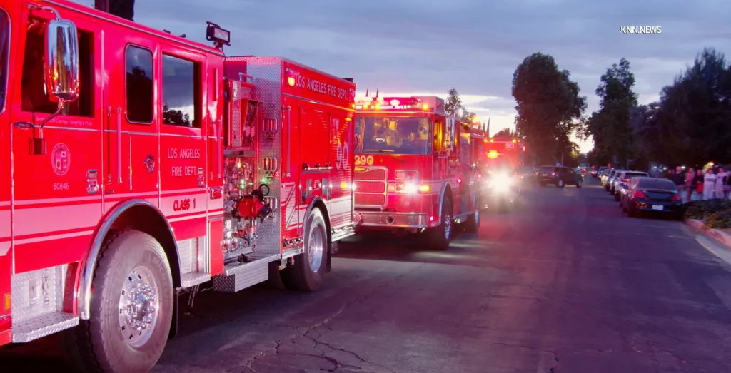 Multiple Los Angeles Fire Department firetrucks on a street at dusk.