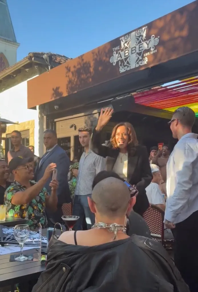 Kamala Harris waving to a crowd outside The Abbey bar and restaurant.