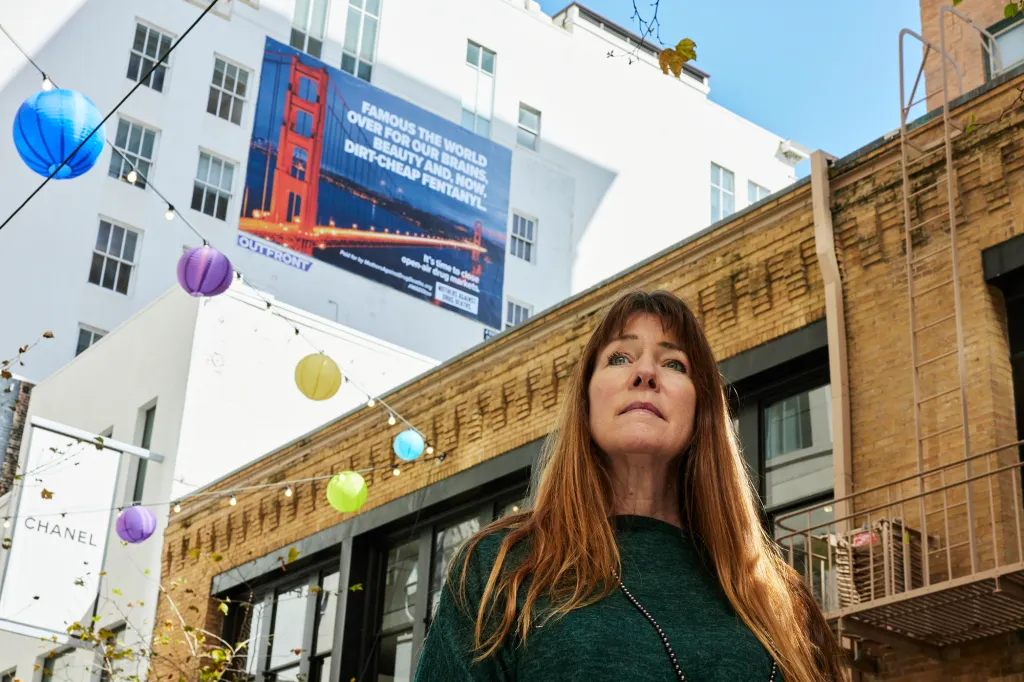 Jacqui Berlinn, co-founder of Mothers Against Drug Deaths, in front of a billboard warning about fentanyl.