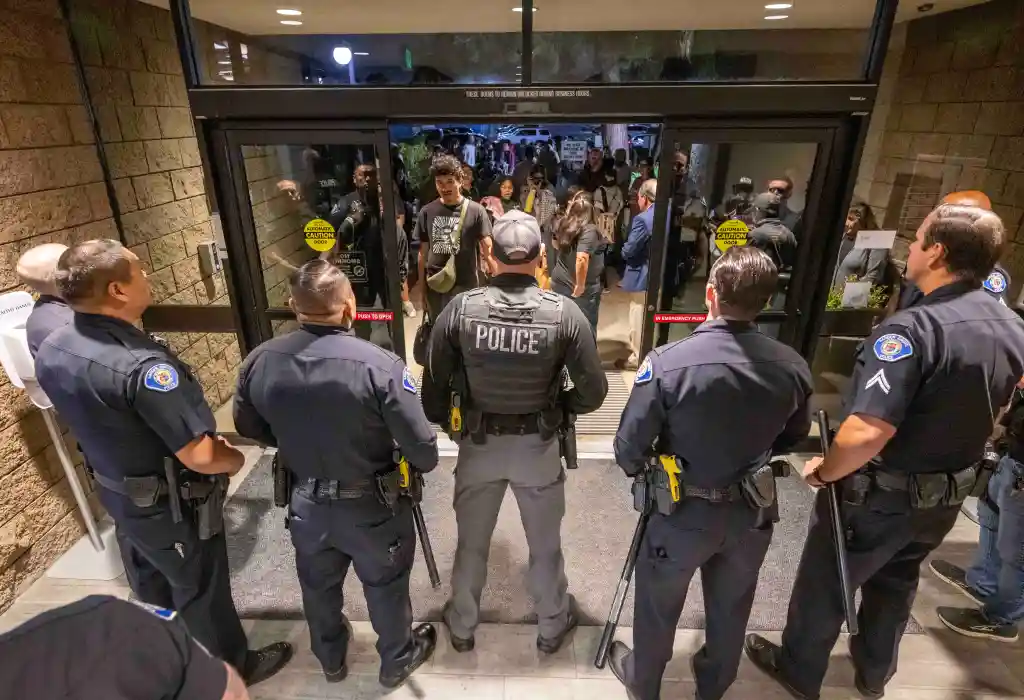 Police officers stand guard at the entrance to a public meeting about a hazmat incident.