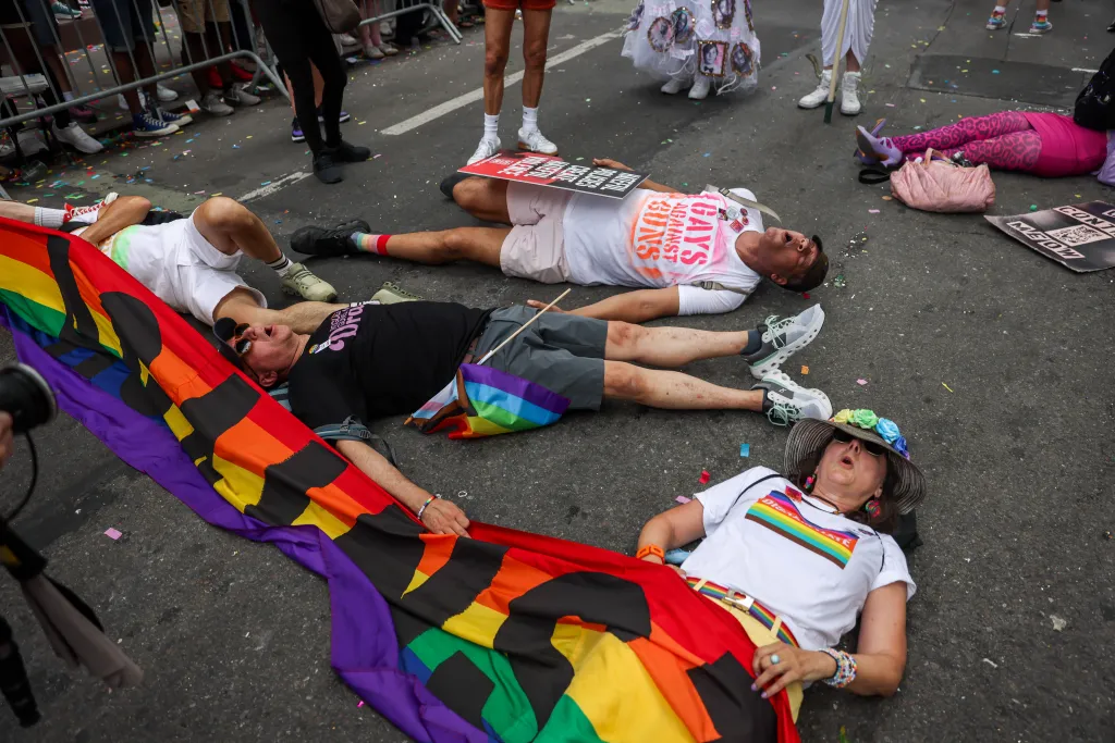 Protesters from Gays Against Guns lie on the ground with pride flags during the 2026 NYC Pride March.