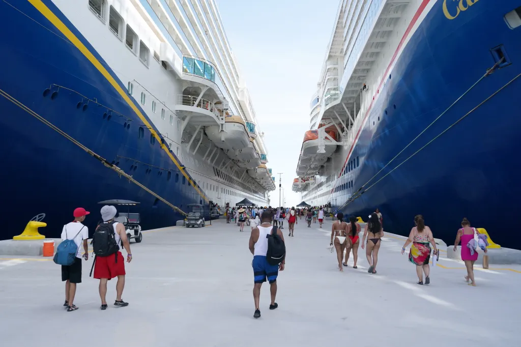 Passengers walking on a dock between the Carnival Venezia and Carnival Celebration cruise ships.