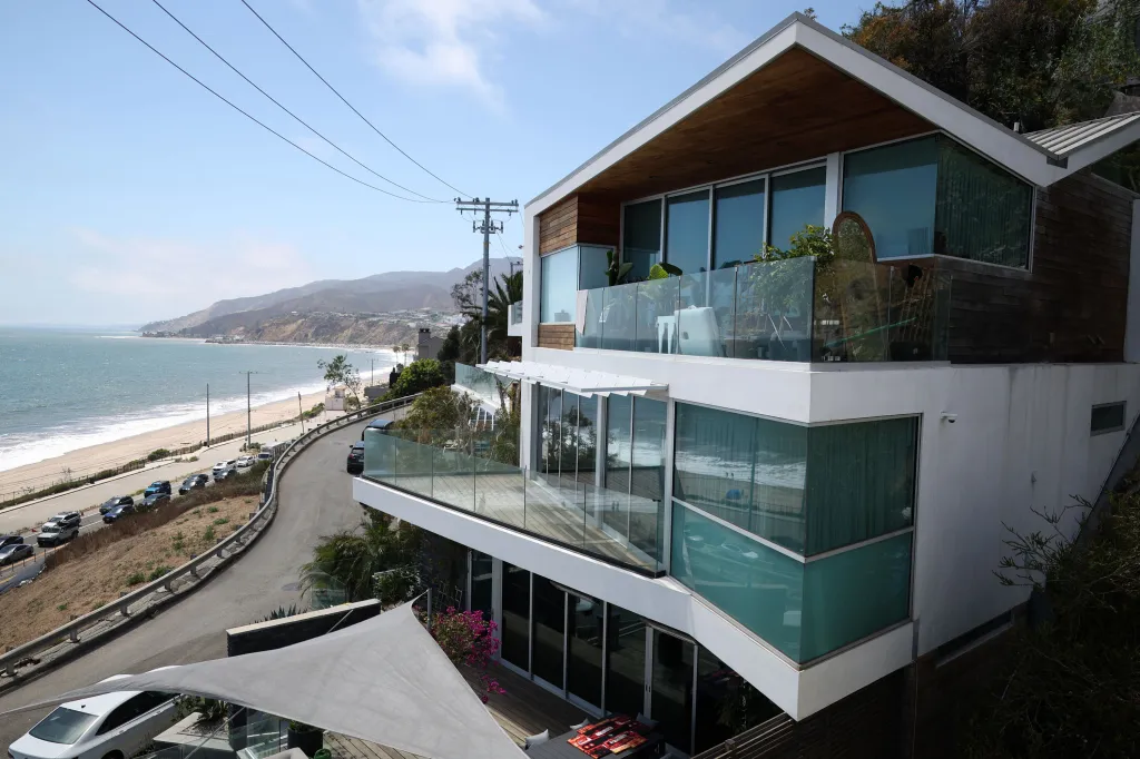 Exterior of a multi-story home with balconies overlooking a coastal road and beach.