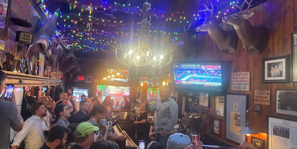 Graham Platner bartending at the Tune Inn, a Washington D.C. bar decorated with mounted fish and deer heads.