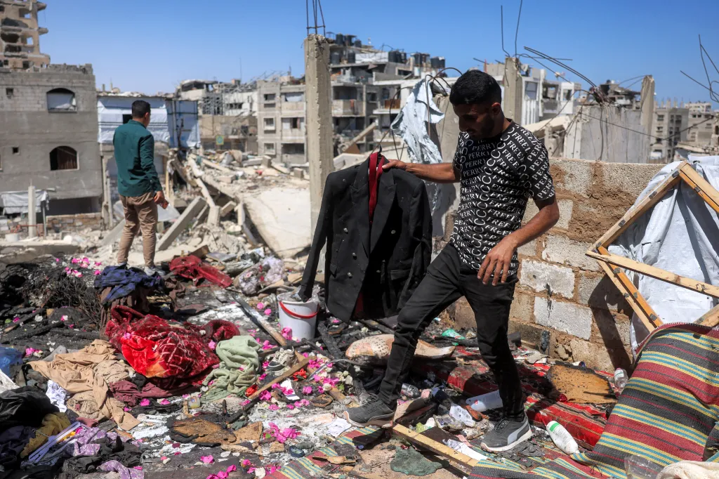 A man holds a black wedding jacket amidst the rubble of a destroyed building in Khan Yunis.