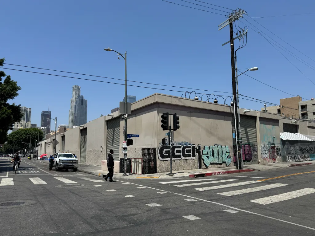 The intersection of 6th Street and San Julian Street in Downtown Los Angeles, where a shooting occurred, showing multiple people, a white truck, and a street with crosswalks and graffiti-covered walls.