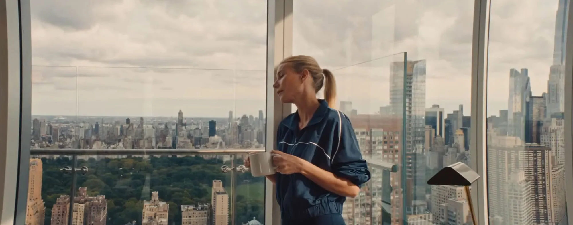 Gwyneth Paltrow looking out a window at a city skyline.