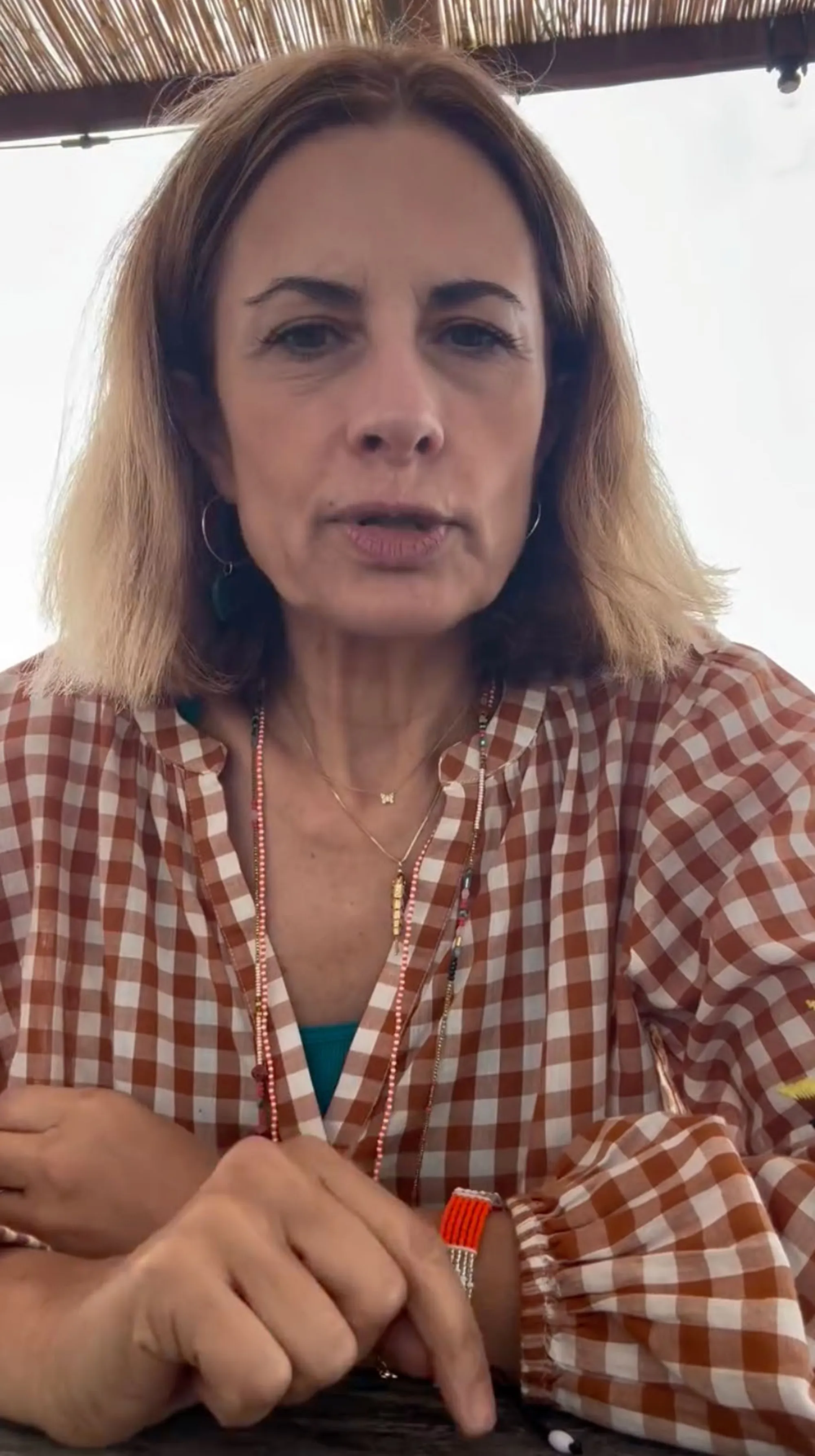 Livia Giuggioli Firth wearing a brown and white gingham shirt and beaded necklaces.