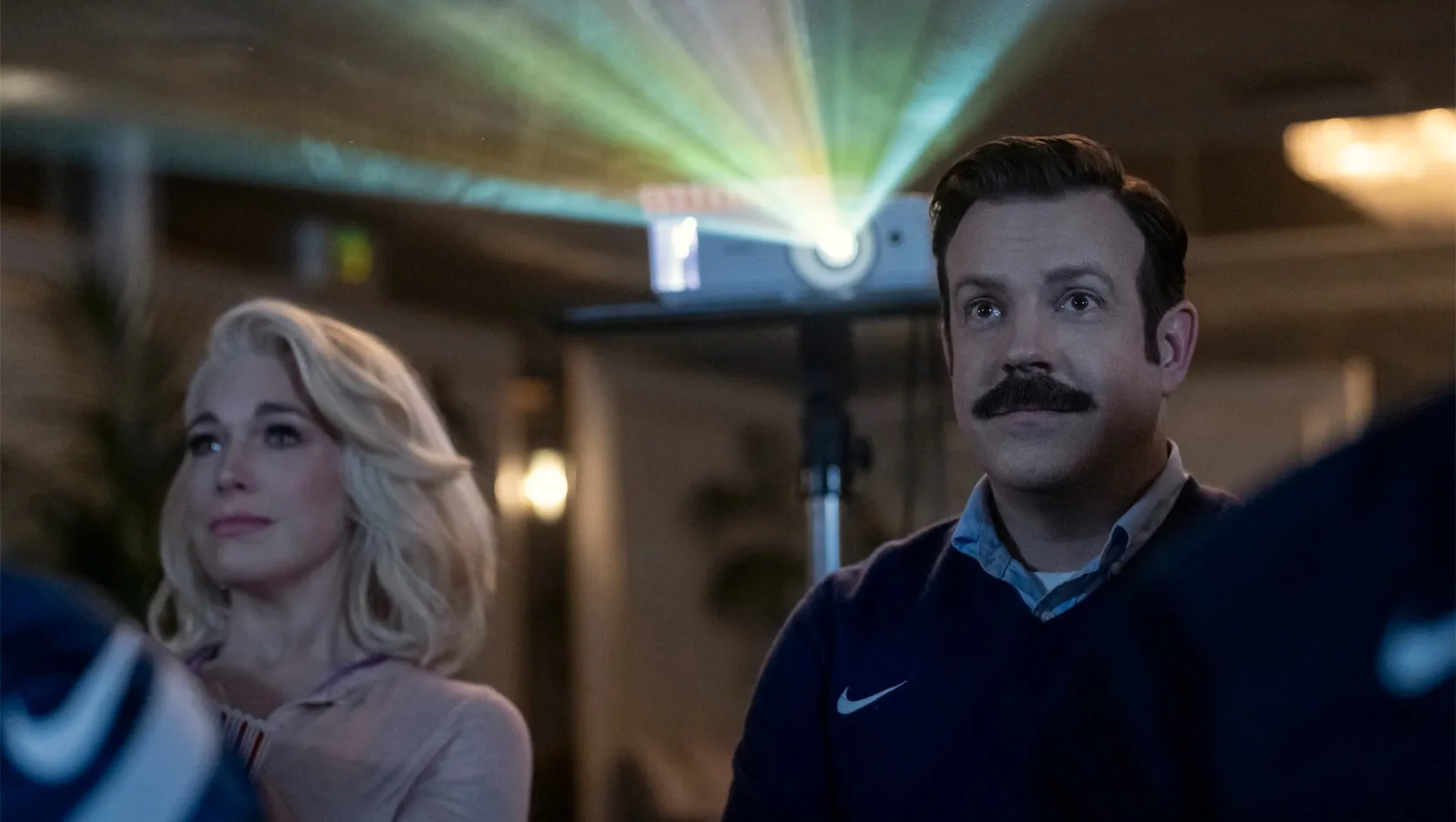 Hannah Waddingham and Jason Sudeikis watching a projection.